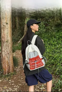 Outdoor leisure backpack in beige and red with mesh side pocket shown in nature