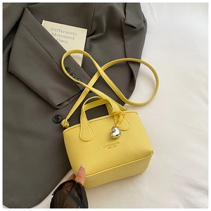 Detail of yellow pebble leather mini bag with silver heart charm and brand logo
