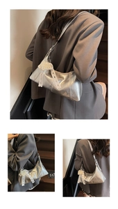 Silver metallic hobo bag with a decorative pearl bow charm and ruffled leather finish
