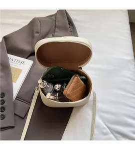 Détail du sac bandoulière crème avec intérieur spacieux montrant téléphone et parfum