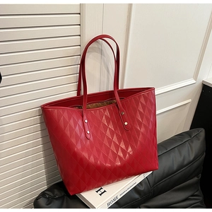 Macro shot of red tote bag with diamond quilted texture and golden rivet details