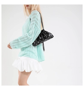 Fashionable black drawstring bucket bag with silver studs worn with a knit sweater