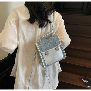 Detail of silver butterfly accents on blue denim and metallic leather crossbody bag