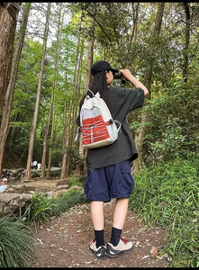 Close-up of lightweight hiking backpack with orange contrast and bungee cord in forest