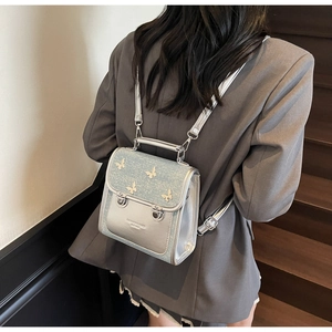 Detailed view of silver glitter backpack with 3D butterfly accents and metal buckle