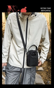 Detail view of black nylon drawstring crossbody bag against a forest backdrop