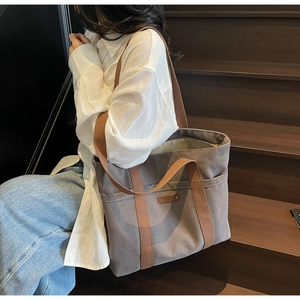 Detailed view of spacious brown canvas tote bag with reinforced handles on wooden steps