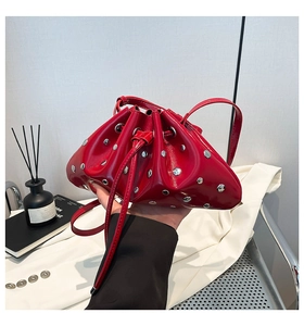Detail of red patent leather bucket bag with silver rivets and drawstring closure