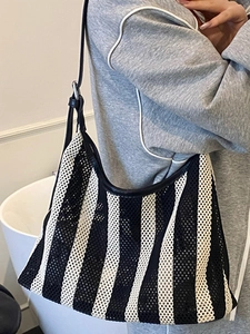 Grand sac cabas en mesh rayé avec anses en cuir noir porté par un mannequin en intérieur