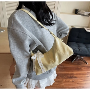 Detail of cream shoulder bag with pleated texture and pearl lace bow charm