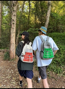 Outdoor backpacks in color-block designs with elastic cords shown in forest setting