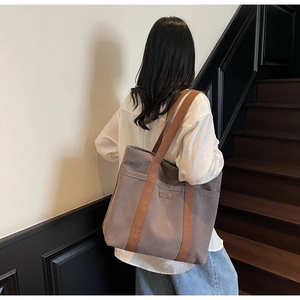 Detailed view of large canvas tote bag with brown straps worn over the shoulder for daily use