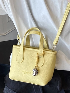 Litchi texture leather yellow small bucket bag with dual handles and metal pendant
