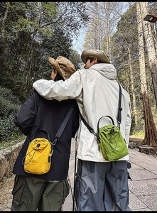 Detail of yellow and olive nylon bucket bags with adjustable straps in nature