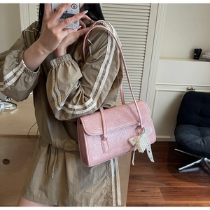 Pink underarm shoulder bag with textured leather and a pearl bow charm accessory