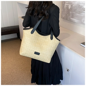 Close-up of woven straw tote bag with black leather straps on model shoulder
