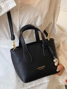 Minimalist black leather bucket handbag with gold logo and adjustable shoulder strap