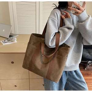 Side view of a large brown canvas tote bag used for commuting in a cozy home studio setting
