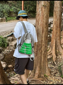 Outdoor hiking backpack with vibrant green drawstring pocket and mesh side bottle holder