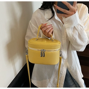 Sac boîte jaune vif avec motif litchi porté par un mannequin et détails argentés