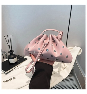 Detail of a bright pink drawstring bucket bag featuring silver rivets and a glossy finish