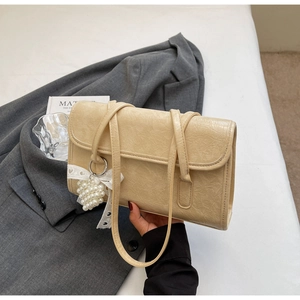 Detail of cream leather shoulder bag with pleated texture and pearl heart charm