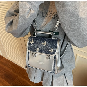 Detail view of denim flap with silver butterflies and metallic silver leather texture
