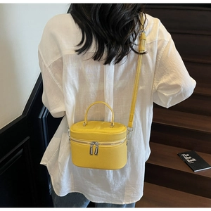 Détail du sac à main jaune vif avec texture cuir litchi et double fermeture éclair