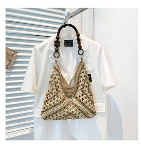 Detail of hand-woven straw tote bag with brown wooden bead handle and lattice texture