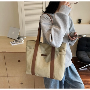 Detail view of large khaki canvas tote bag with brown straps in office setting