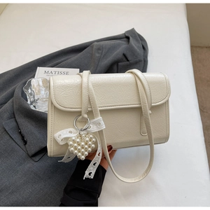 Detail of off-white pleated leather shoulder bag with pearl heart pendant and bow