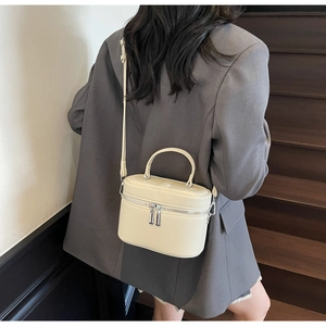 Sac bandoulière blanc crème grainé porté avec un blazer gris dans un escalier