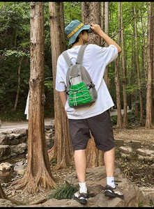 Detail of grey outdoor backpack with vibrant neon green drawstring pocket in nature