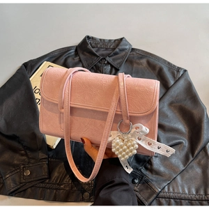 Detail of pink pleated shoulder bag featuring a pearl heart charm and lace ribbon
