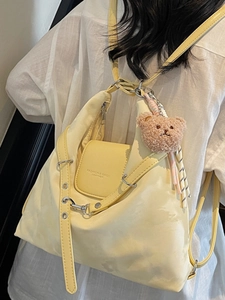 Minimalistischer cremefarbener Rucksack mit Schnalle und Plüschbär-Anhänger