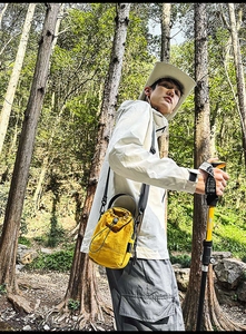 Close-up of bright yellow drawstring bucket bag worn during an outdoor forest hiking session