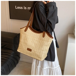 Detail of hand-woven straw tote bag with brown leather handles and smooth texture