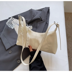 Detail of off-white wrinkled PU leather bag with pearl and lace bow pendant accessory