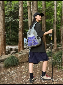 Hiking backpack detail featuring purple bungee cords and side mesh pocket in forest setting