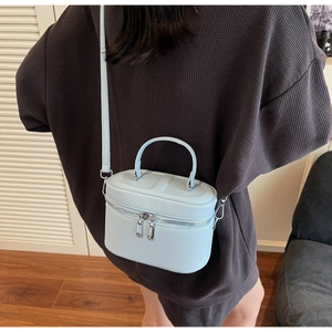 Détail du sac boîte bleu clair à motif litchi avec zips argentés et poignée haute