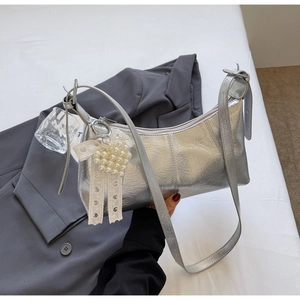 Detailed macro view of silver metallic bag featuring pearl heart charm and lace ribbon