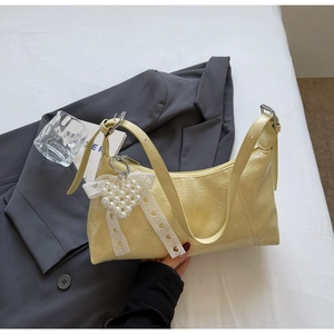 Close-up of yellow wrinkled leather bag with pearl heart and lace bow detail