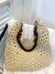Large hand-woven straw tote bag with round wooden bead handles and floral hollow patterns