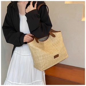 Close-up of woven straw tote bag with vertical texture and dark brown leather straps