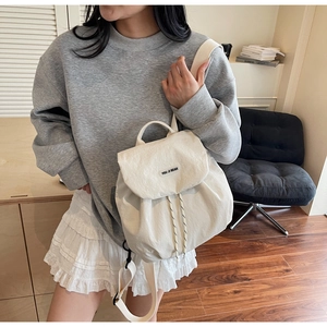 Dettaglio dello zaino in nylon crema con chiusura a patta ed etichetta nera