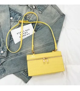 Detail view of yellow faux crocodile pattern box bag on blue denim jacket
