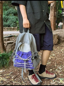 Detail view of the gray and purple waterproof hiking backpack with white bungee cords