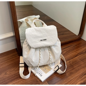 Dettaglio dello zaino in nylon bianco sporco con chiusura a coulisse e patch su libro d'arte