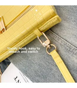 Detail of yellow crocodile embossed leather bag with gold metal hook and strap
