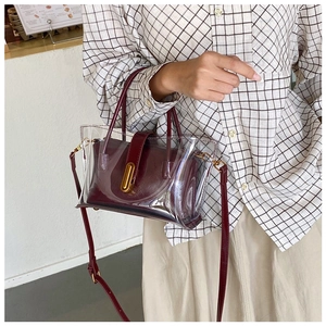 Close-up of clear PVC tote with burgundy inner pouch and gold twist lock detail